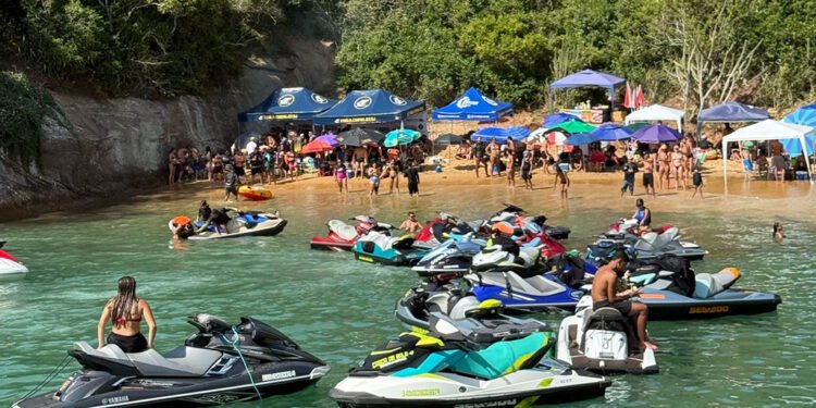 Grupo de jet skis navegando próximo à Ilha do Francês, em Macaé, com vegetação tropical e formações rochosas ao fundo