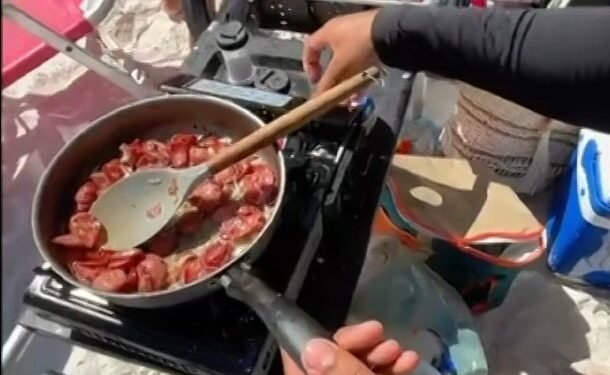 Turistas preparam linguiça acebolada na Praia do Forte, em Cabo Frio